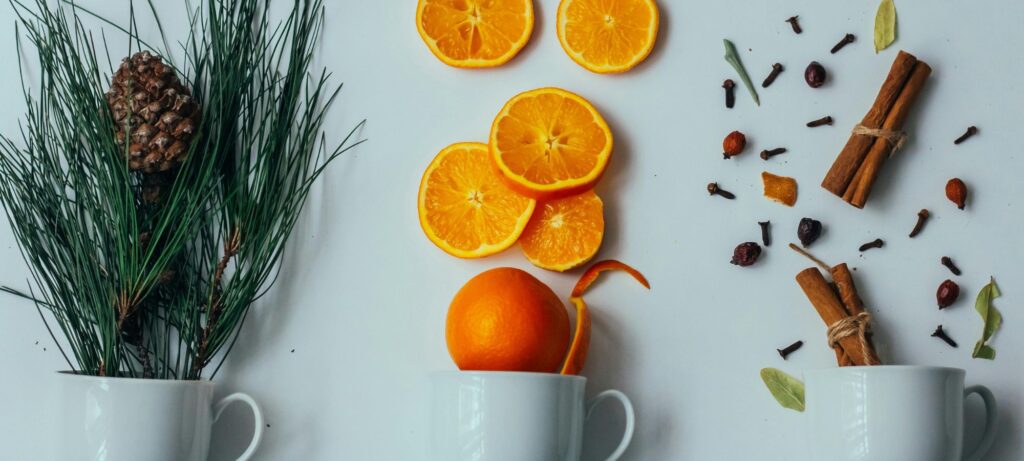 mugs holding natural elements like oranges, pine branches, and cinnamon sticks
